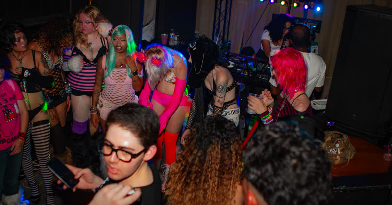A packed dance floor under colorful lights at Dress to Impress, photographed by Jay Snaps