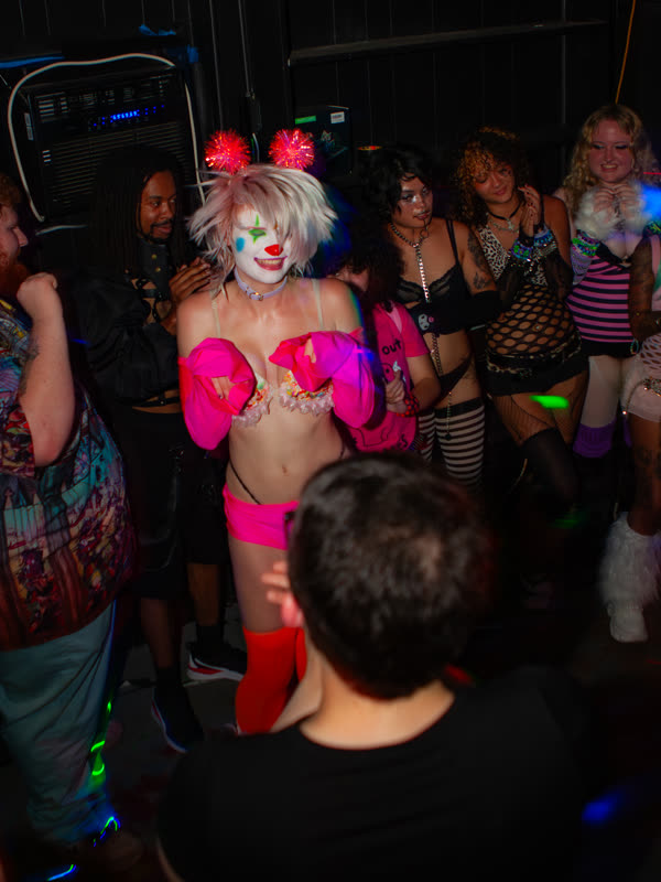 Guest in a pink outfit surrounded by the crowd at Dress to Impress, photographed by Jay Snaps