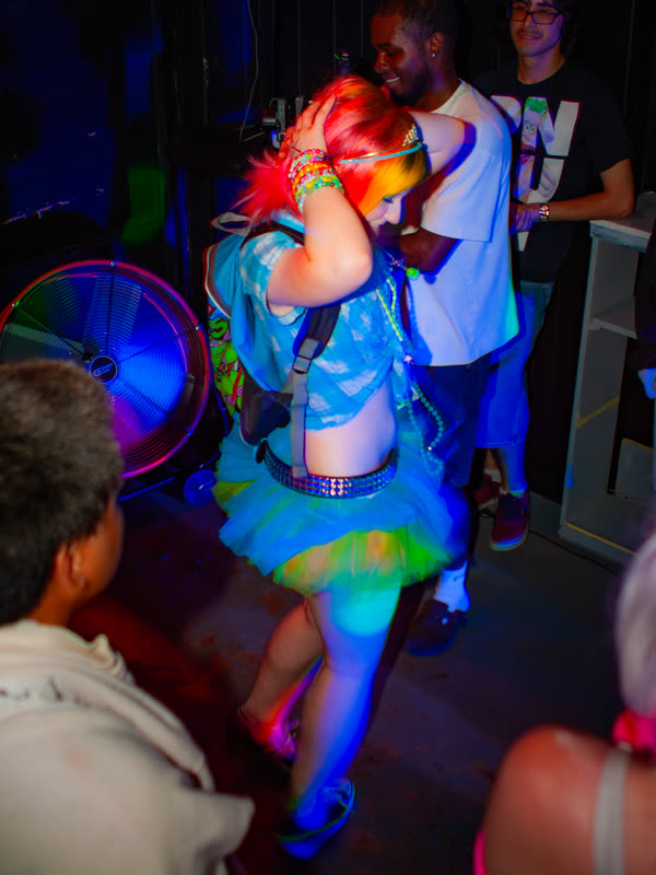 Guest dancing in a colorful blue and green outfit at Dress to Impress, photographed by Jay Snaps