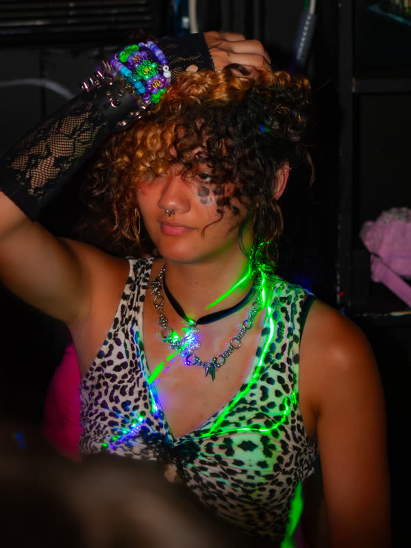 Guest wearing a leopard-print top and glowing necklaces at Dress to Impress, photographed by Jay Snaps